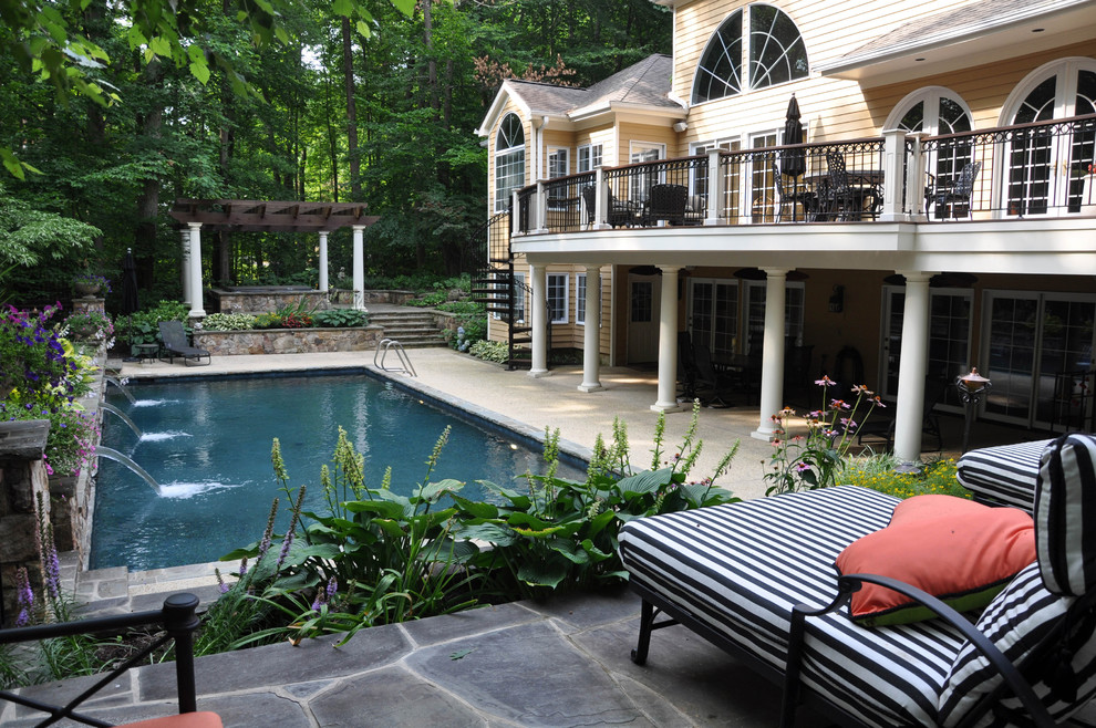 Diseño de piscina con fuente alargada de estilo americano extra grande rectangular en patio trasero con adoquines de piedra natural
