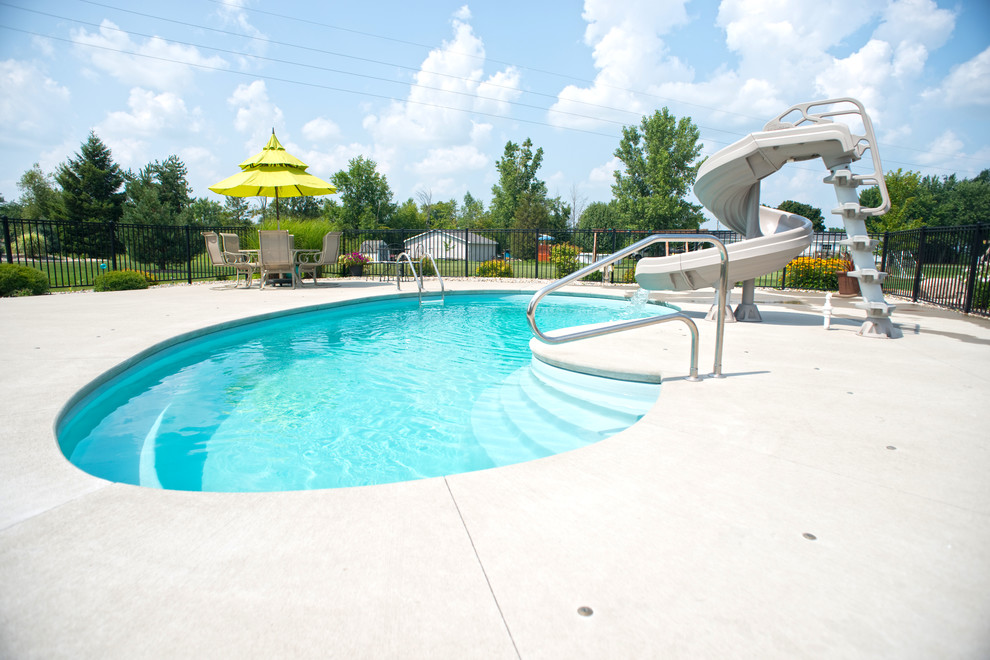 Idee per una piscina moderna a "C" di medie dimensioni e dietro casa con un acquascivolo e lastre di cemento