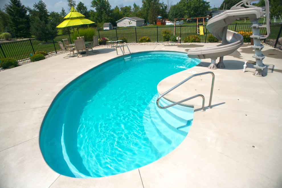 Esempio di una piscina moderna a "C" di medie dimensioni e dietro casa con un acquascivolo e lastre di cemento