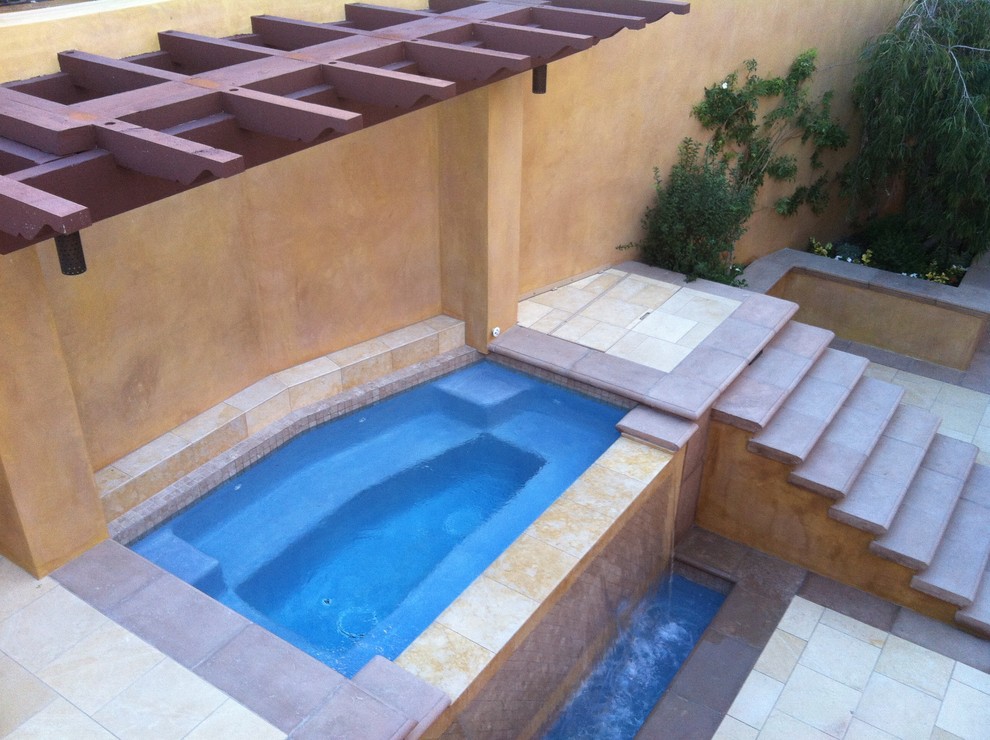 Design ideas for a large mediterranean back custom shaped infinity hot tub in Orange County with tiled flooring.