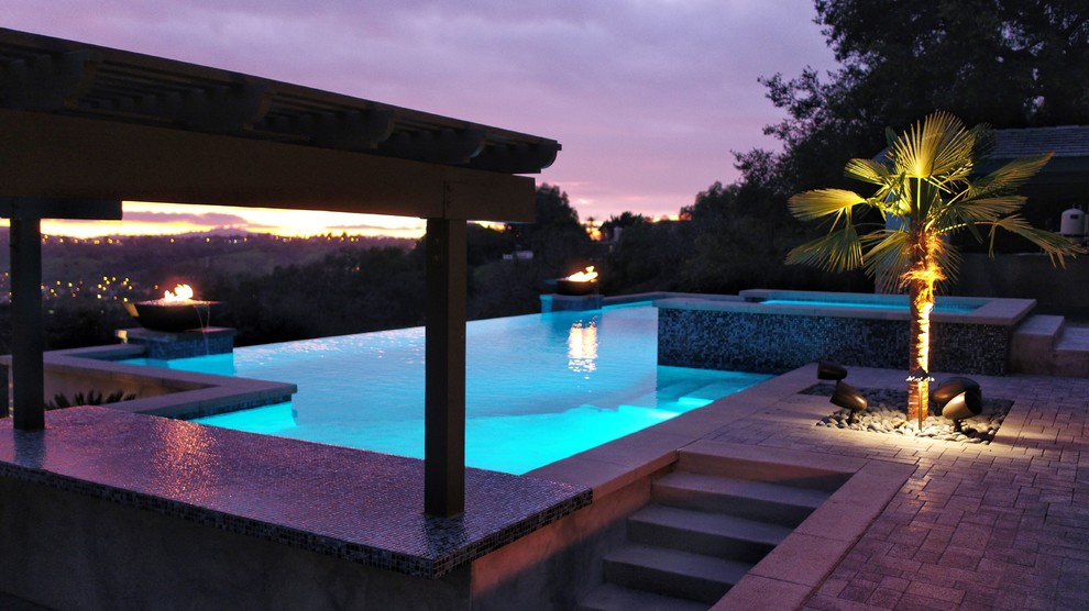 Immagine di una grande piscina a sfioro infinito contemporanea rettangolare dietro casa con una vasca idromassaggio e pavimentazioni in cemento