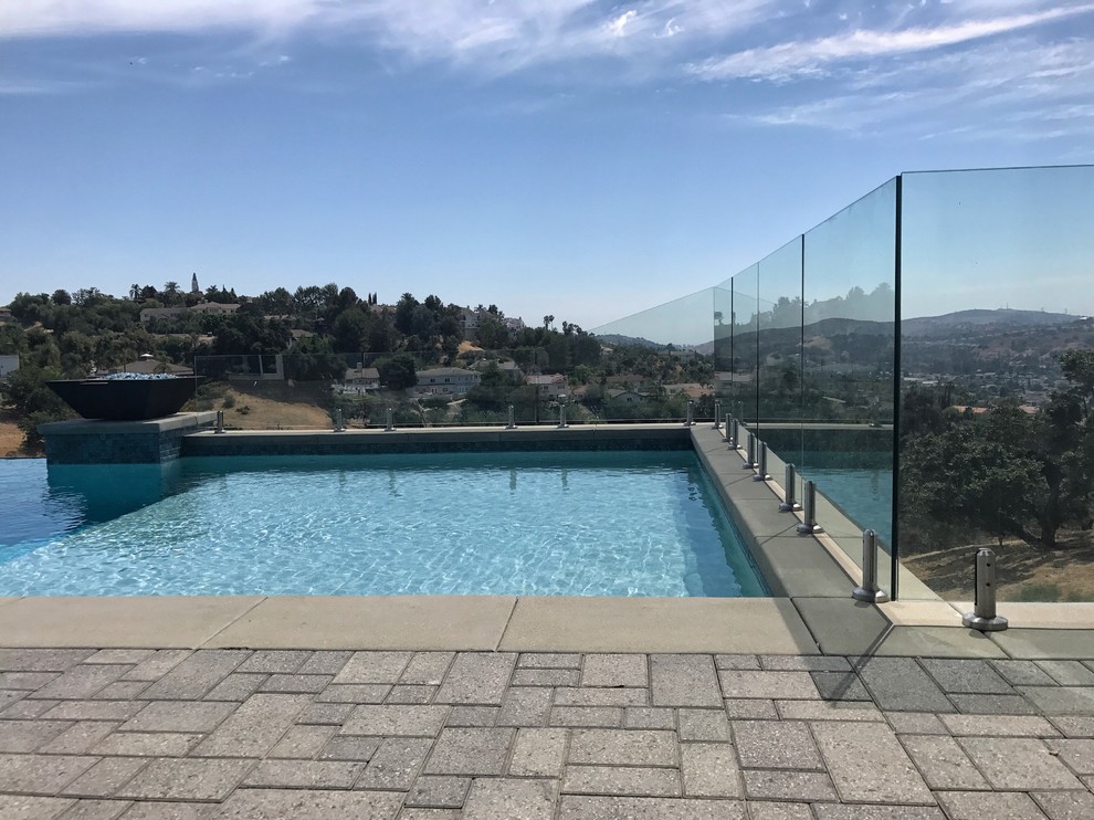 Foto de piscinas y jacuzzis infinitos contemporáneos grandes rectangulares en patio trasero con adoquines de hormigón