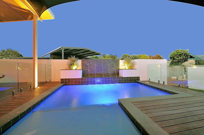 Cette photo montre une piscine arrière tendance en L de taille moyenne avec un point d'eau et une terrasse en bois.