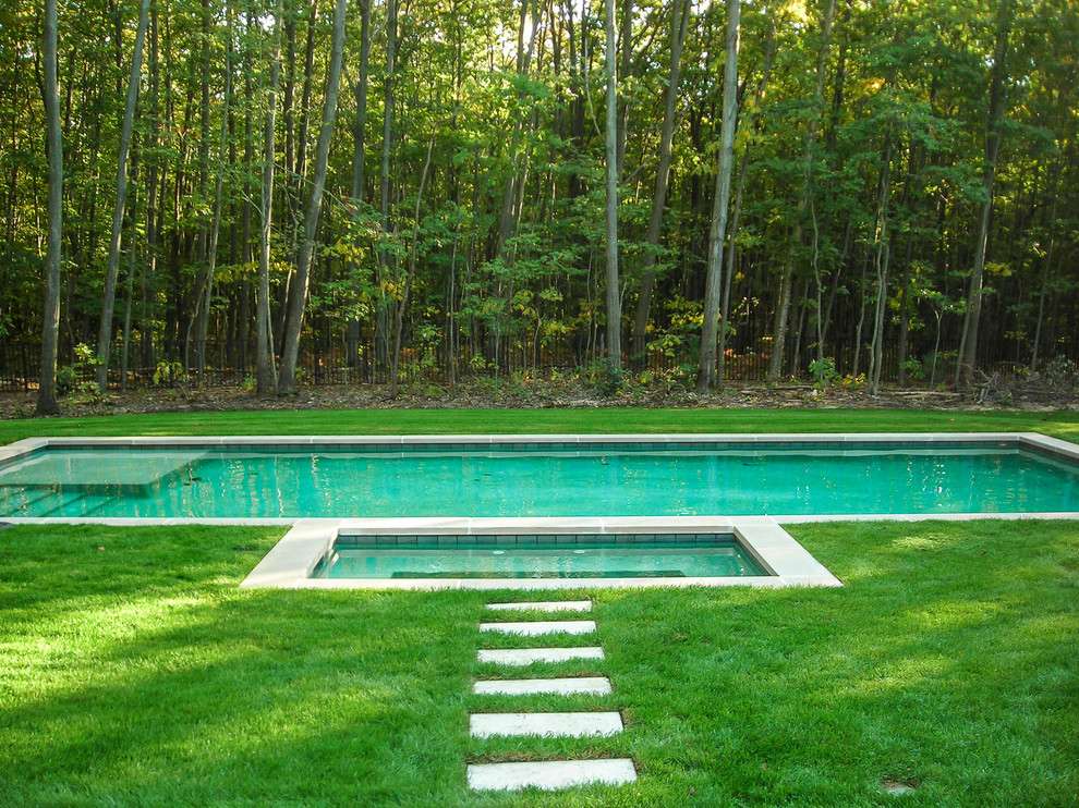 Aménagement d'une grande piscine naturelle classique sur mesure avec un point d'eau, une cour et des pavés en béton.