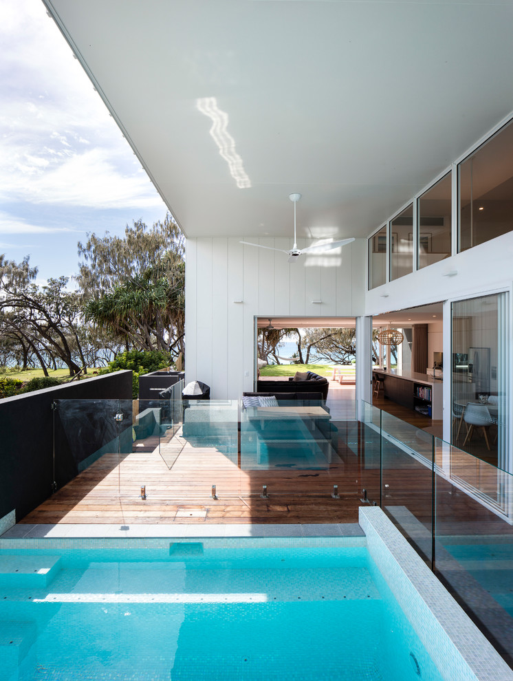 Cette image montre une grande piscine naturelle et arrière design avec une terrasse en bois.