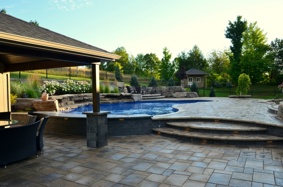 Large nautical back custom shaped swimming pool in Toronto with a water feature and concrete paving.