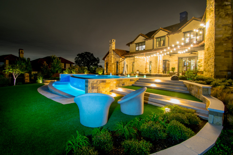 Стильный дизайн: большой бассейн-инфинити произвольной формы на заднем дворе в стиле неоклассика (современная классика) с фонтаном и покрытием из каменной брусчатки - последний тренд