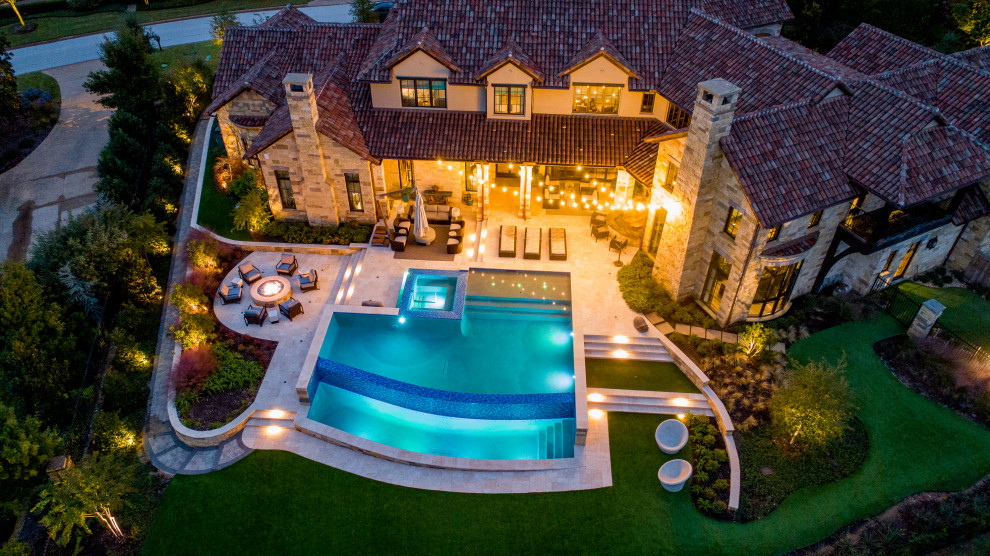 Modelo de piscina con fuente infinita clásica renovada grande a medida en patio trasero con adoquines de piedra natural