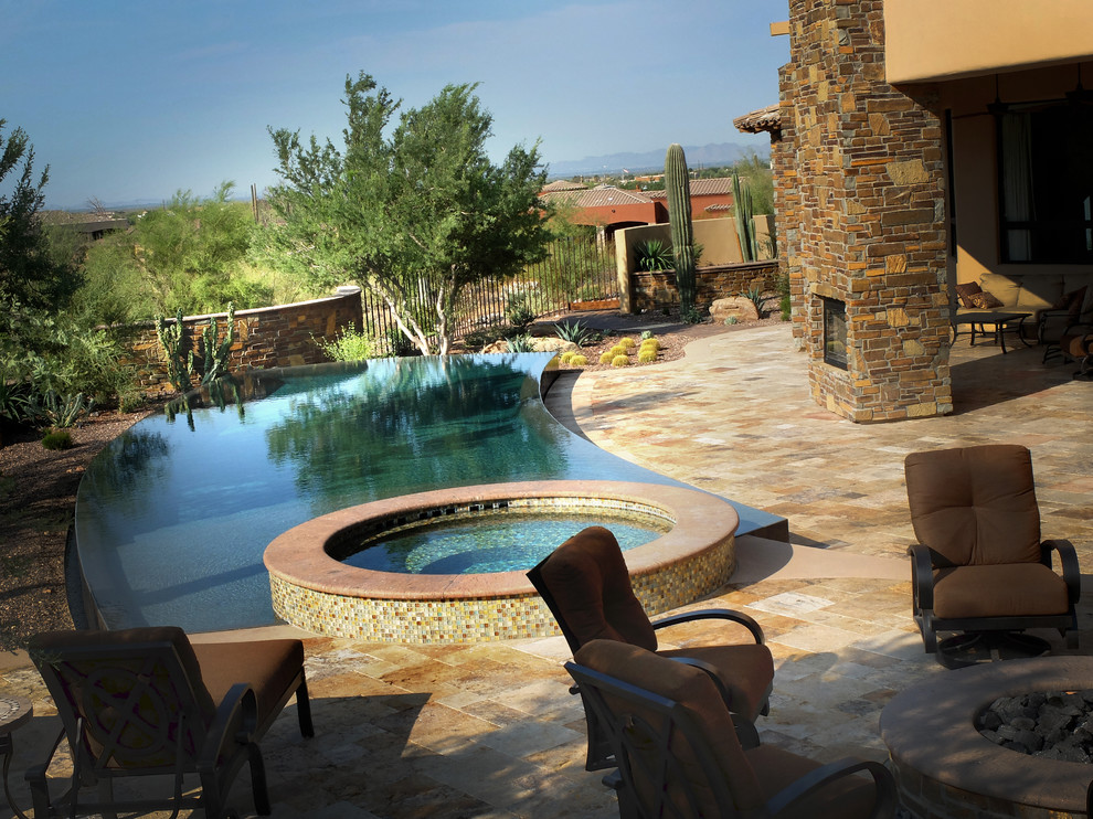 Inspiration for a huge southwestern backyard stone and custom-shaped infinity hot tub remodel in Phoenix