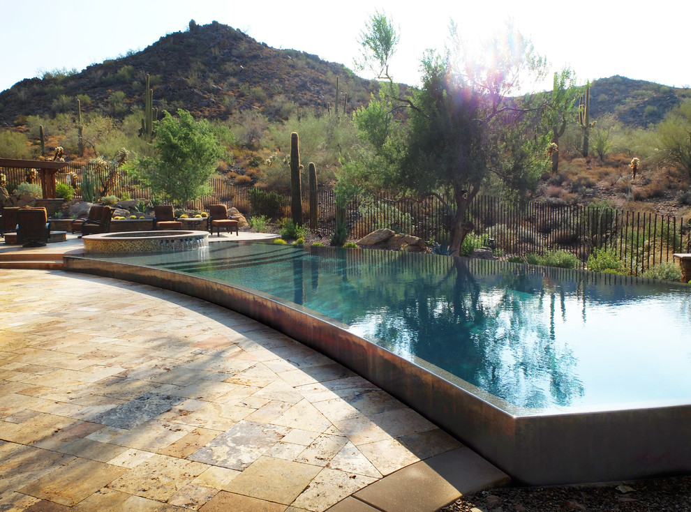 Ejemplo de piscinas y jacuzzis infinitos de estilo americano extra grandes a medida en patio trasero con adoquines de piedra natural