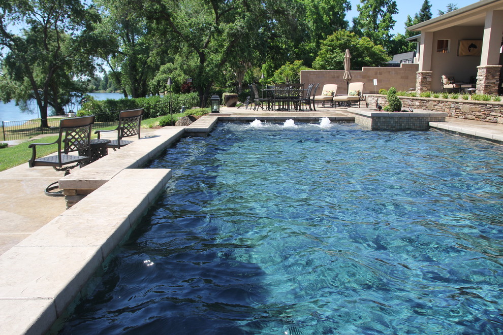 Ejemplo de piscina con fuente elevada actual de tamaño medio rectangular en patio trasero con losas de hormigón
