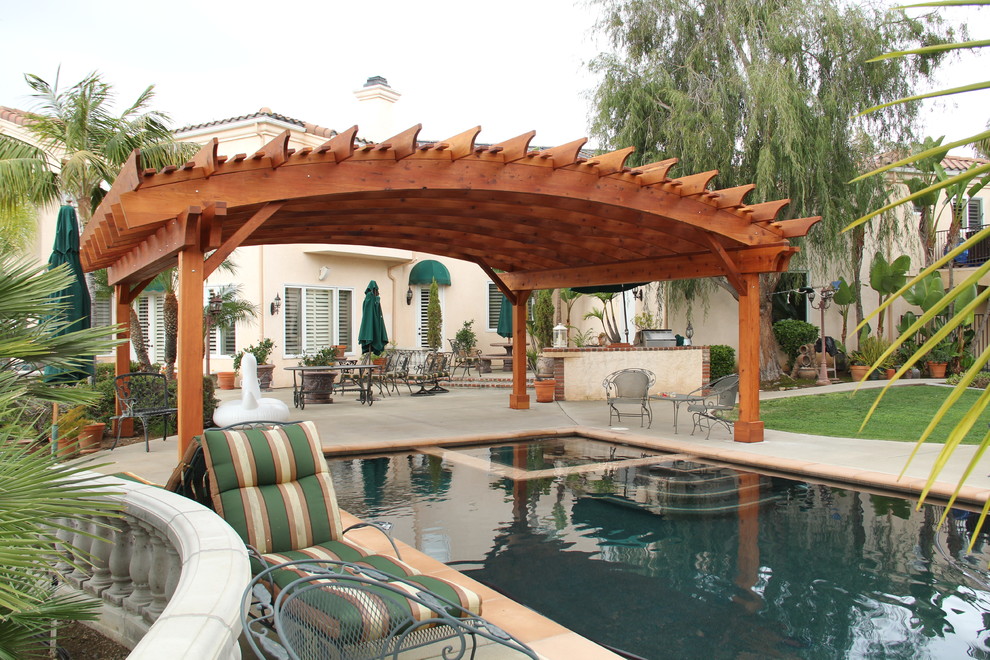 Foto de casa de la piscina y piscina de estilo americano extra grande a medida en patio trasero con losas de hormigón