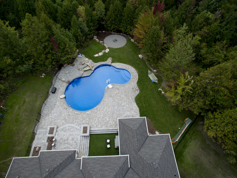 Imagen de piscina con fuente natural minimalista grande tipo riñón en patio trasero con suelo de hormigón estampado