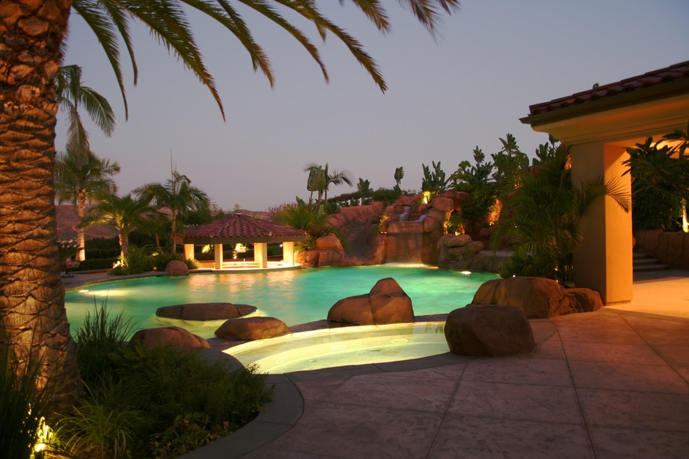 Large world-inspired back custom shaped swimming pool in Orange County with a water feature and stamped concrete.