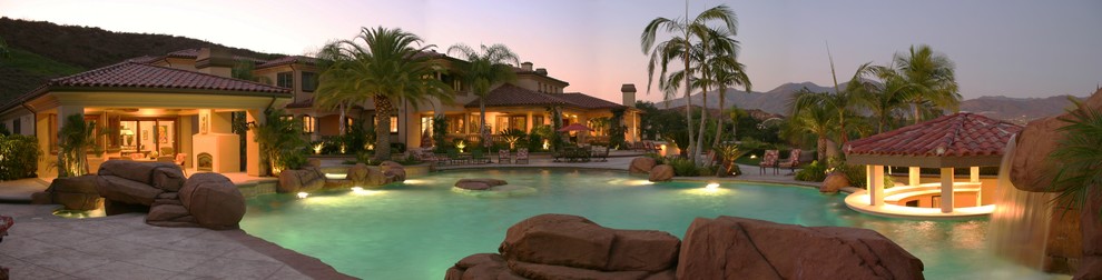 Foto på en stor tropisk pool på baksidan av huset, med en fontän och stämplad betong