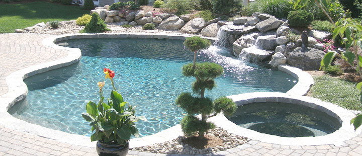 Bild på en stor funkis anpassad pool på baksidan av huset, med spabad och stämplad betong