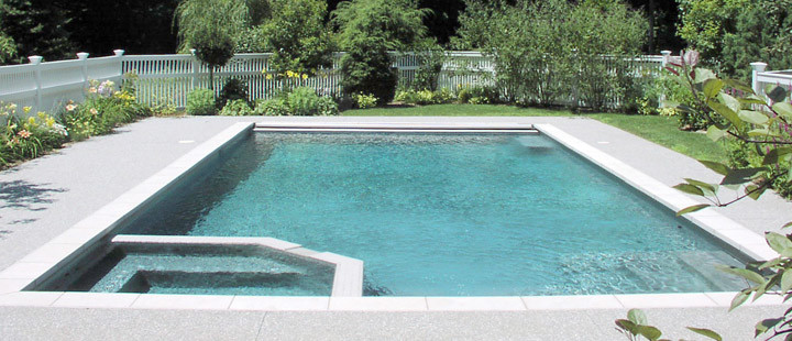 Idée de décoration pour une grande piscine arrière minimaliste sur mesure avec un bain bouillonnant et du béton estampé.