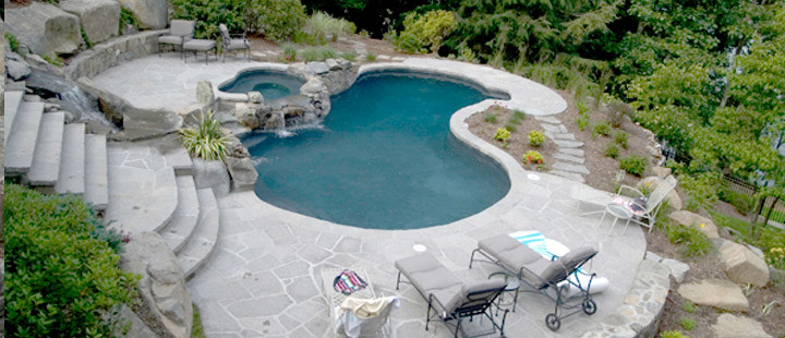 Modelo de piscinas y jacuzzis modernos grandes a medida en patio trasero con suelo de hormigón estampado