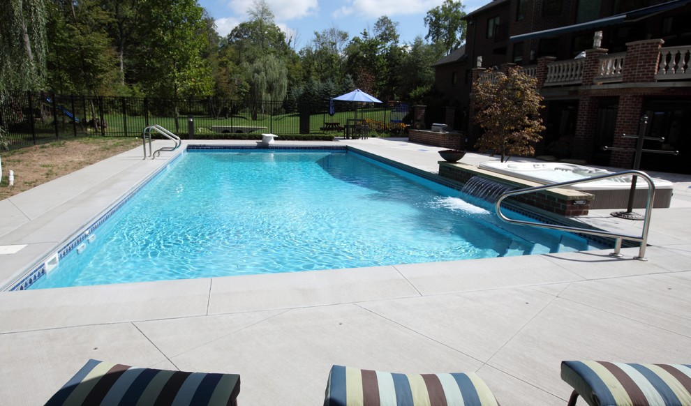На фото: прямоугольный бассейн на заднем дворе в средиземноморском стиле с джакузи и покрытием из бетонных плит с