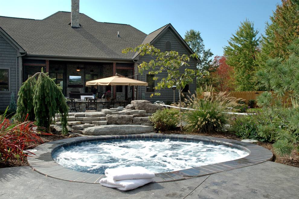 This is an example of a medium sized rustic back hot tub in Cleveland with concrete slabs.