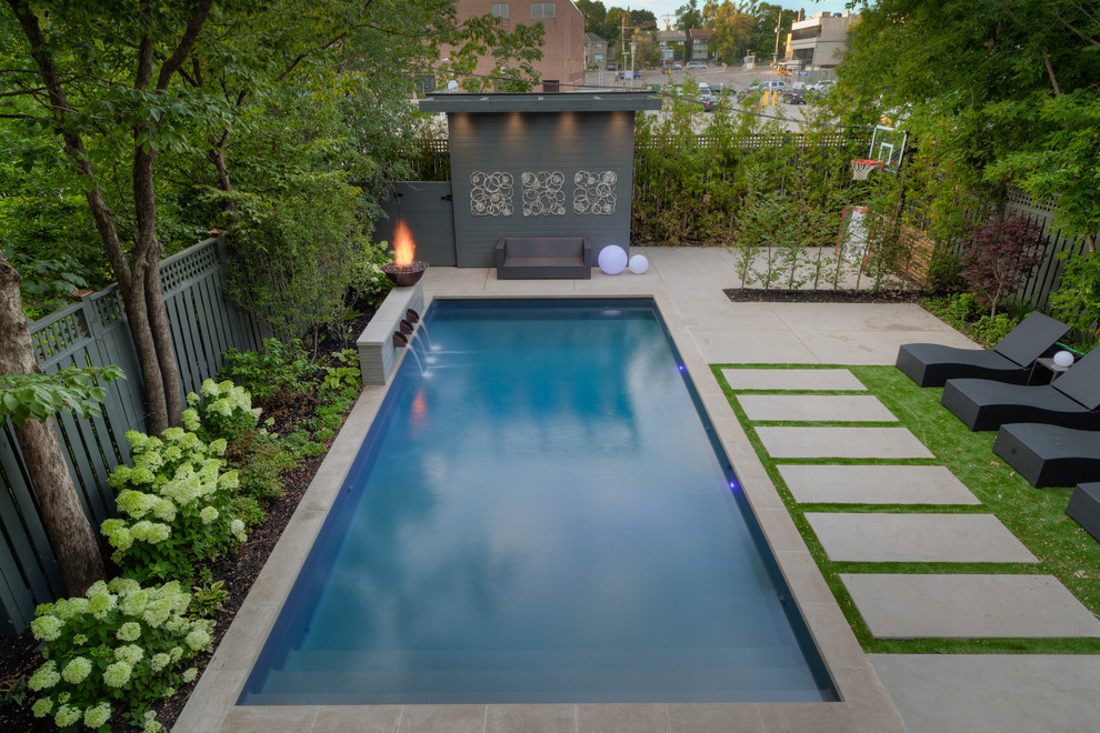 Modelo de piscina con fuente alargada contemporánea de tamaño medio rectangular en patio trasero con adoquines de hormigón