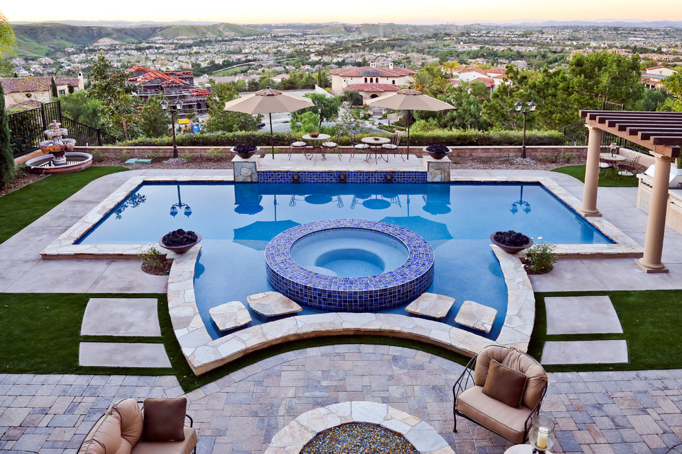 Immagine di una piscina naturale chic personalizzata dietro casa e di medie dimensioni con una vasca idromassaggio e pavimentazioni in pietra naturale