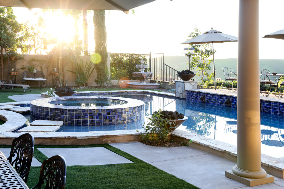 Esempio di una piscina naturale tradizionale personalizzata dietro casa e di medie dimensioni con una vasca idromassaggio e pavimentazioni in pietra naturale