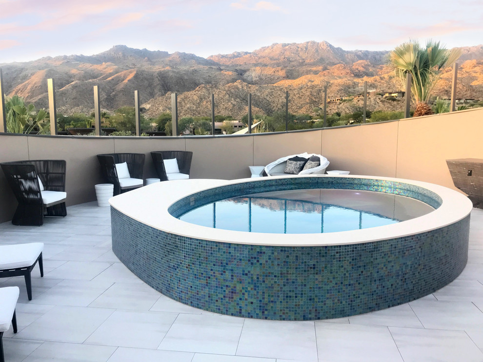 Immagine di una piscina fuori terra design rotonda sul tetto con una vasca idromassaggio e piastrelle