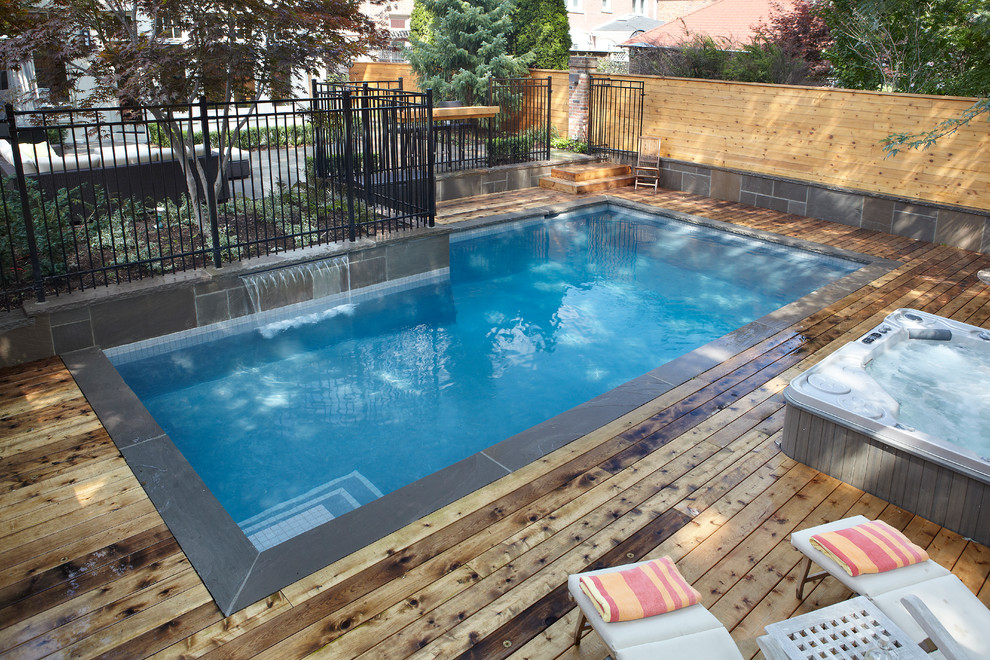 Foto di una piscina monocorsia design rettangolare di medie dimensioni e dietro casa con una vasca idromassaggio e pavimentazioni in cemento