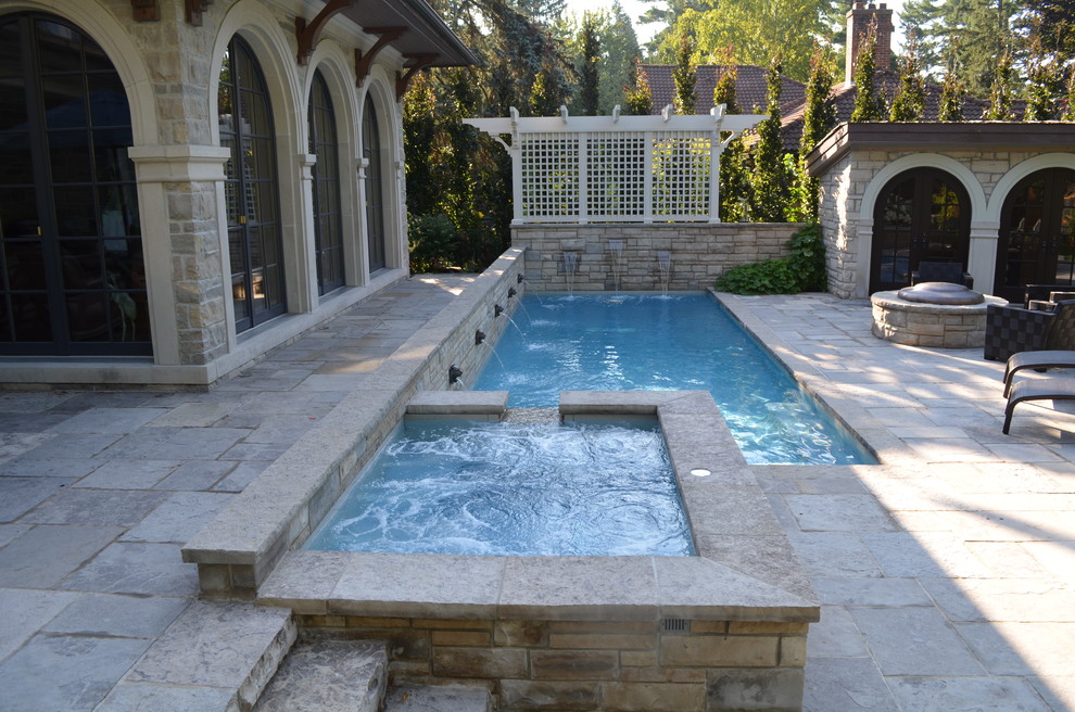 На фото: прямоугольный бассейн среднего размера на заднем дворе в классическом стиле с фонтаном и покрытием из каменной брусчатки