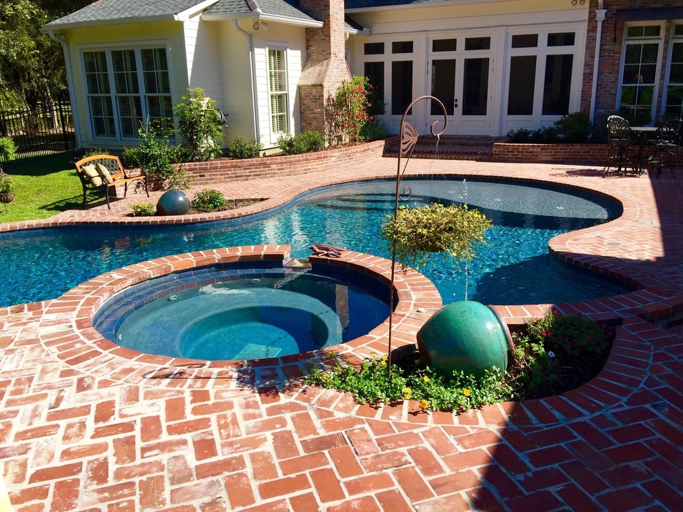 Idées déco pour une grande piscine arrière classique sur mesure avec un bain bouillonnant et des pavés en brique.