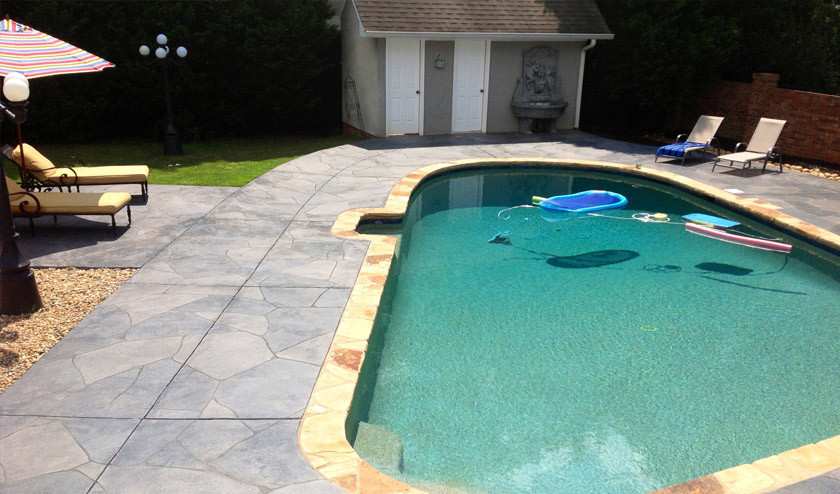 Ejemplo de piscina de estilo americano en patio trasero con adoquines de hormigón