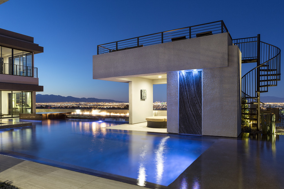 Immagine di un'ampia piscina a sfioro infinito design personalizzata dietro casa con una vasca idromassaggio