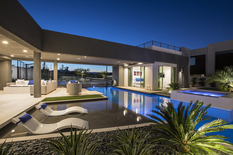 Esempio di un'ampia piscina a sfioro infinito contemporanea personalizzata dietro casa con un acquascivolo e piastrelle