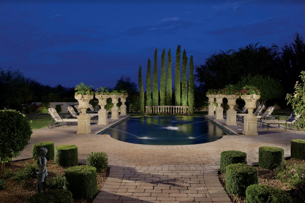 Modelo de piscina con fuente alargada clásica grande rectangular en patio trasero con adoquines de ladrillo