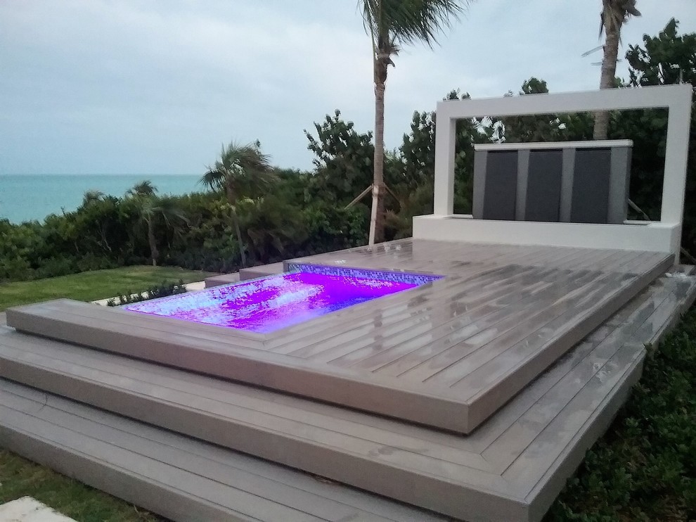 This is an example of a small contemporary back custom shaped infinity hot tub in Other with tiled flooring.