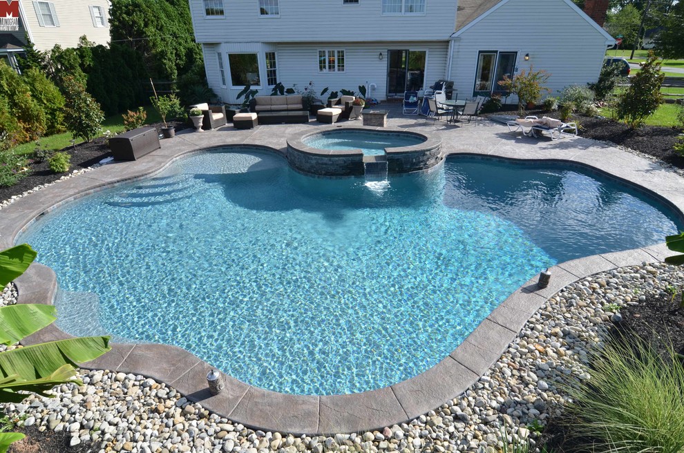 Diseño de piscinas y jacuzzis actuales grandes a medida en patio trasero con suelo de hormigón estampado