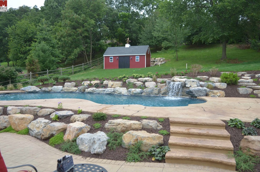 Modern inredning av en stor anpassad pool på baksidan av huset, med en fontän och stämplad betong