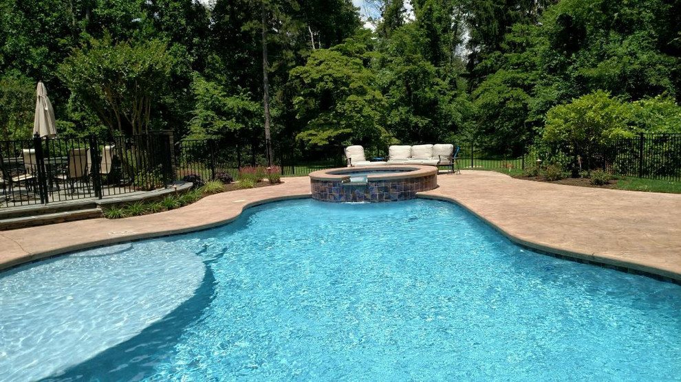 Diseño de piscinas y jacuzzis tradicionales renovados de tamaño medio a medida en patio trasero con losas de hormigón