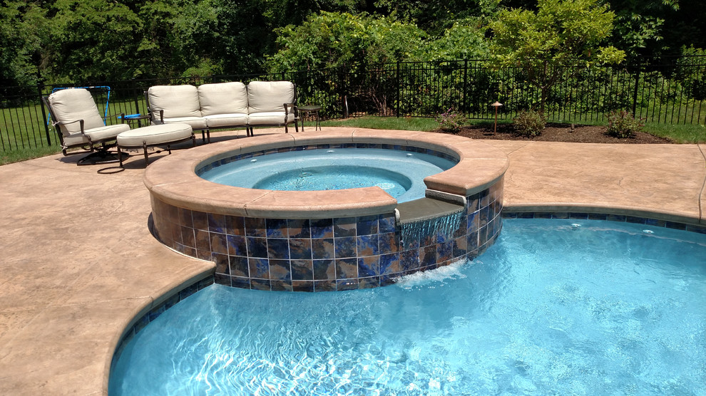 Aménagement d'une piscine arrière classique de taille moyenne et sur mesure avec un bain bouillonnant et une dalle de béton.