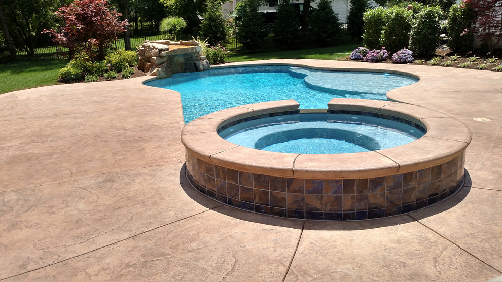 Foto de piscinas y jacuzzis clásicos de tamaño medio a medida en patio trasero con losas de hormigón