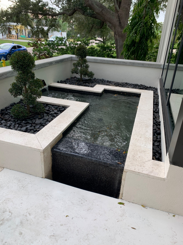 Modelo de piscina con fuente vintage de tamaño medio en forma de L en patio delantero con adoquines de piedra natural