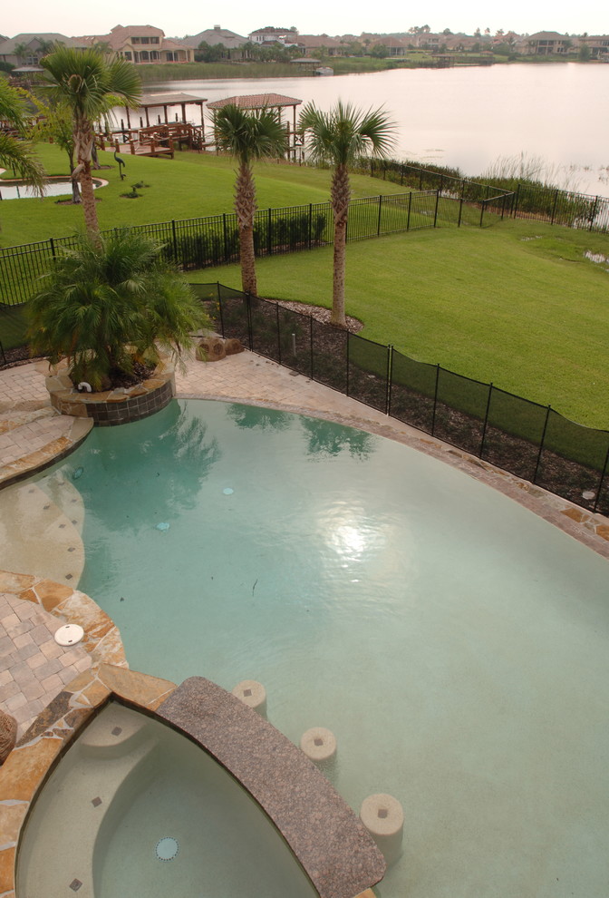 Immagine di un'ampia piscina tropicale personalizzata dietro casa con pavimentazioni in mattoni