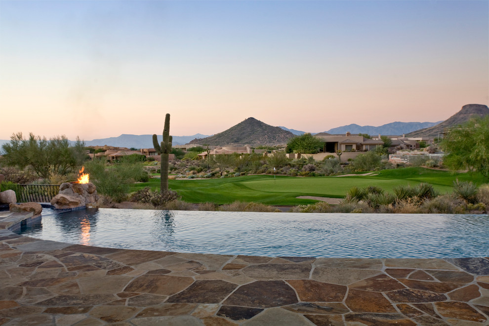 Imagen de piscina infinita de estilo americano tipo riñón en patio trasero con adoquines de piedra natural