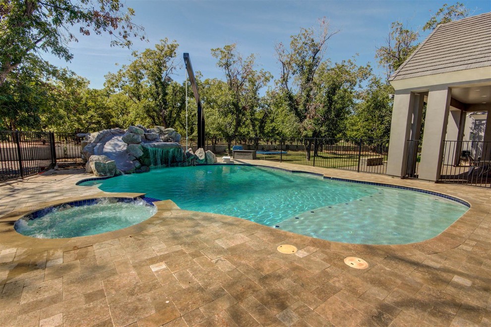 Immagine di una grande piscina naturale american style personalizzata dietro casa con fontane e pavimentazioni in cemento