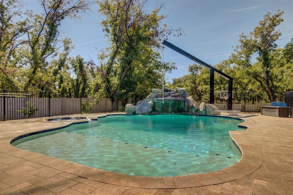 Ejemplo de piscina con fuente natural de estilo americano grande a medida en patio trasero con adoquines de hormigón