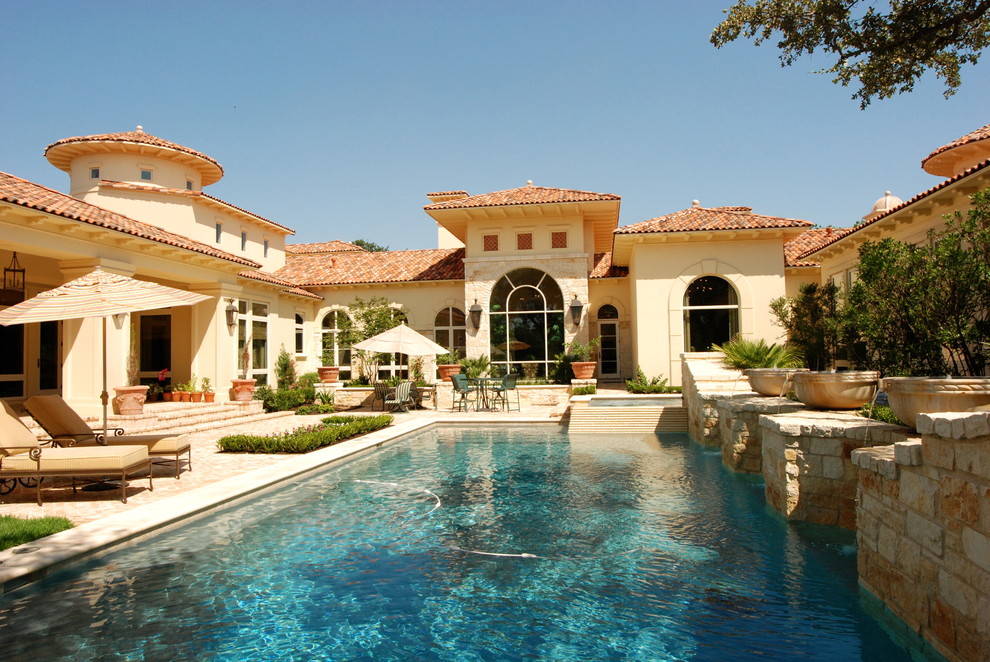 Example of a large tuscan backyard stone and rectangular lap pool fountain design in Austin