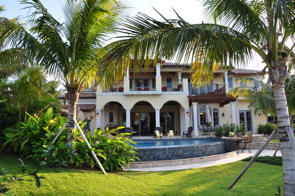 Bild på en stor medelhavsstil anpassad infinitypool på baksidan av huset, med naturstensplattor