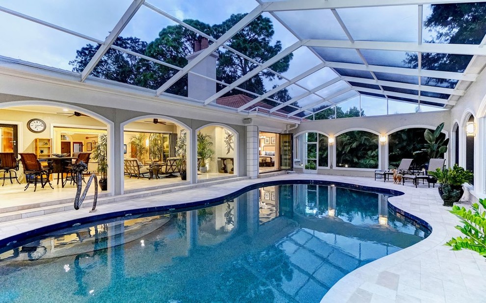 Ejemplo de piscina alargada clásica grande a medida en patio trasero con losas de hormigón