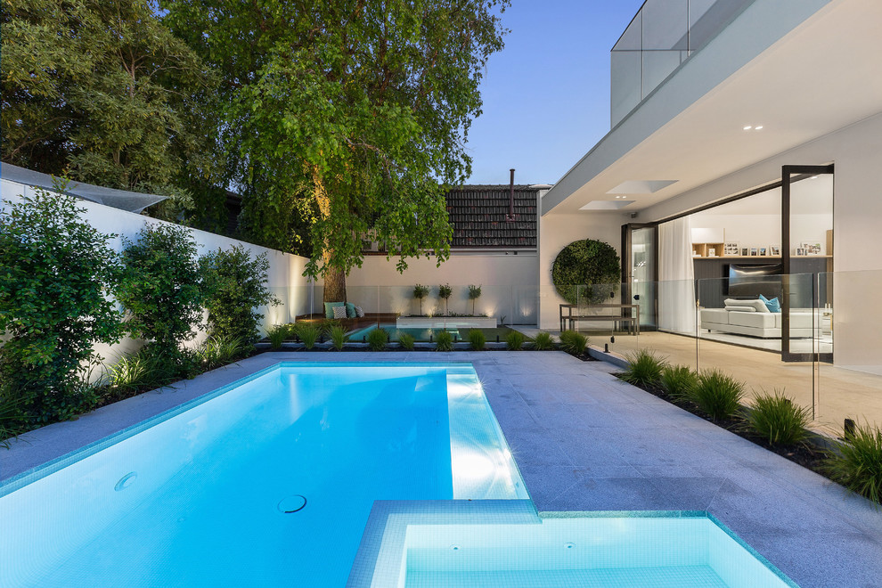 Imagen de piscinas y jacuzzis modernos grandes rectangulares en patio trasero con adoquines de piedra natural